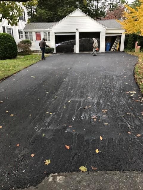 A man is walking down a driveway in front of a garage.