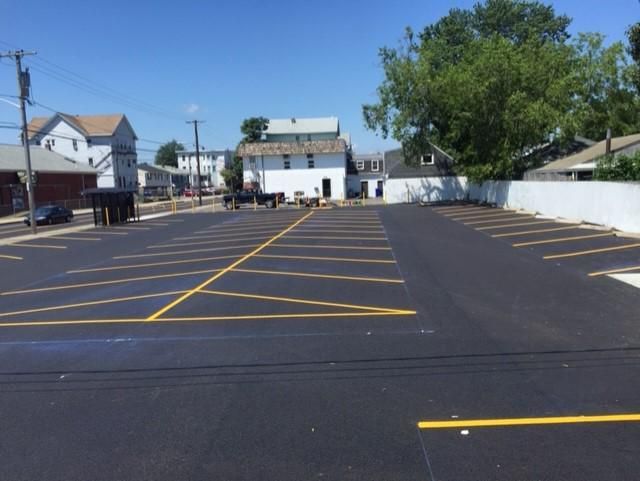 A parking lot with yellow lines and a white building in the background