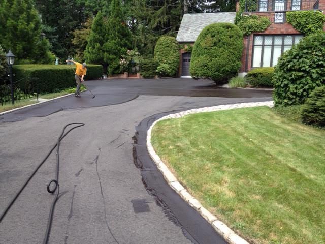 A man is walking down a curved driveway in front of a house.