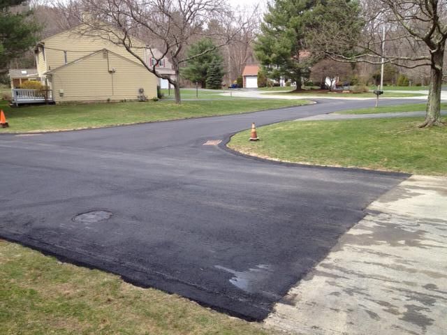 A newly paved driveway with a house in the background