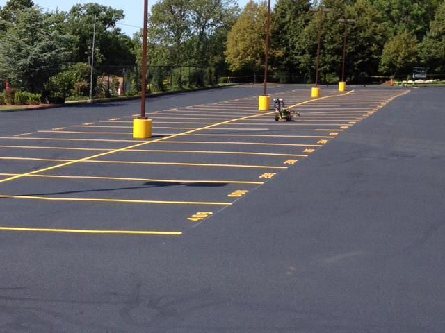 A parking lot with yellow lines and trees in the background