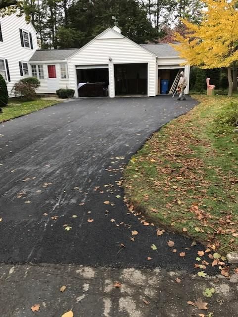 A driveway leading to a white house with a garage.