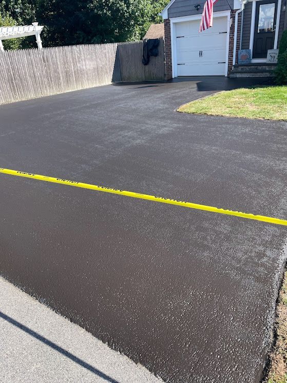 A black driveway with a yellow line in front of a house.