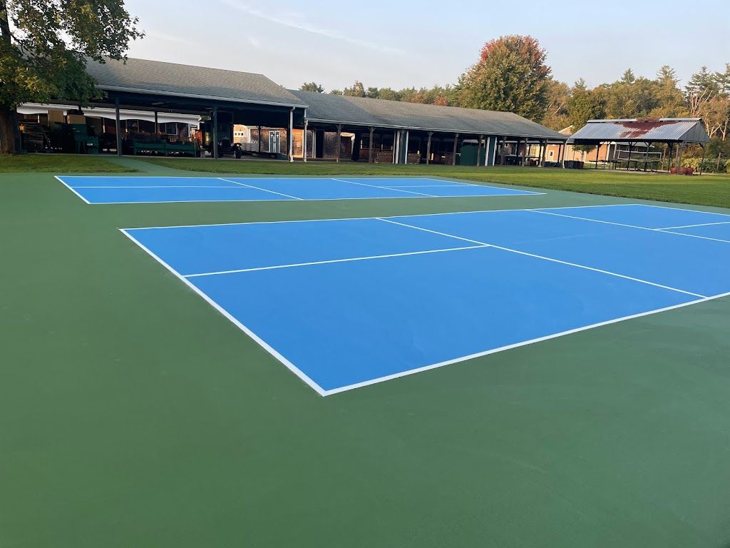 A tennis court with blue and white lines and a building in the background.