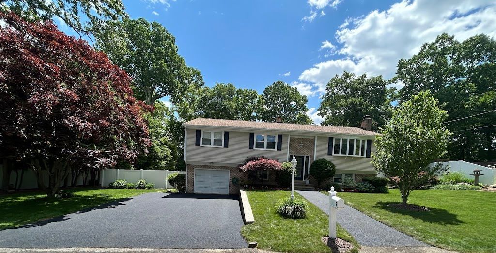 A house with a driveway and trees in front of it
