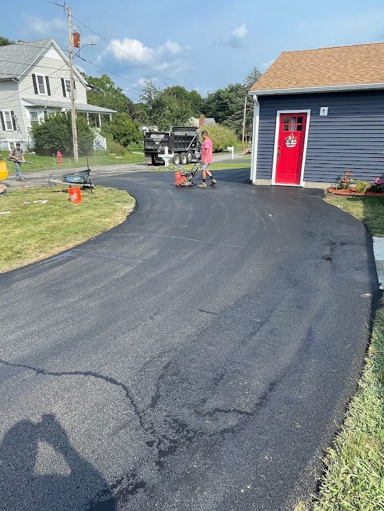 A man is standing in a driveway next to a house.