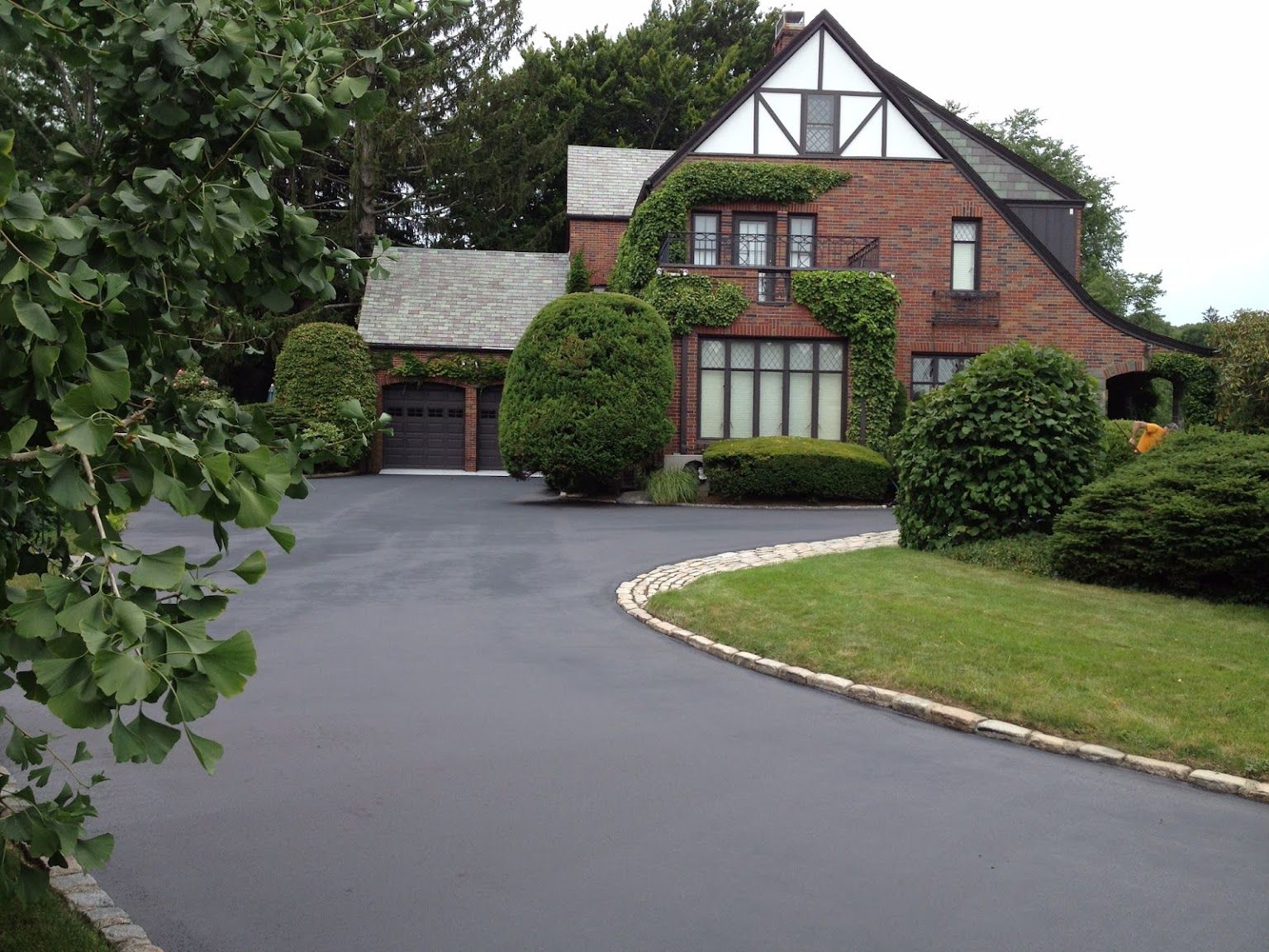 A large brick house with a curved driveway in front of it