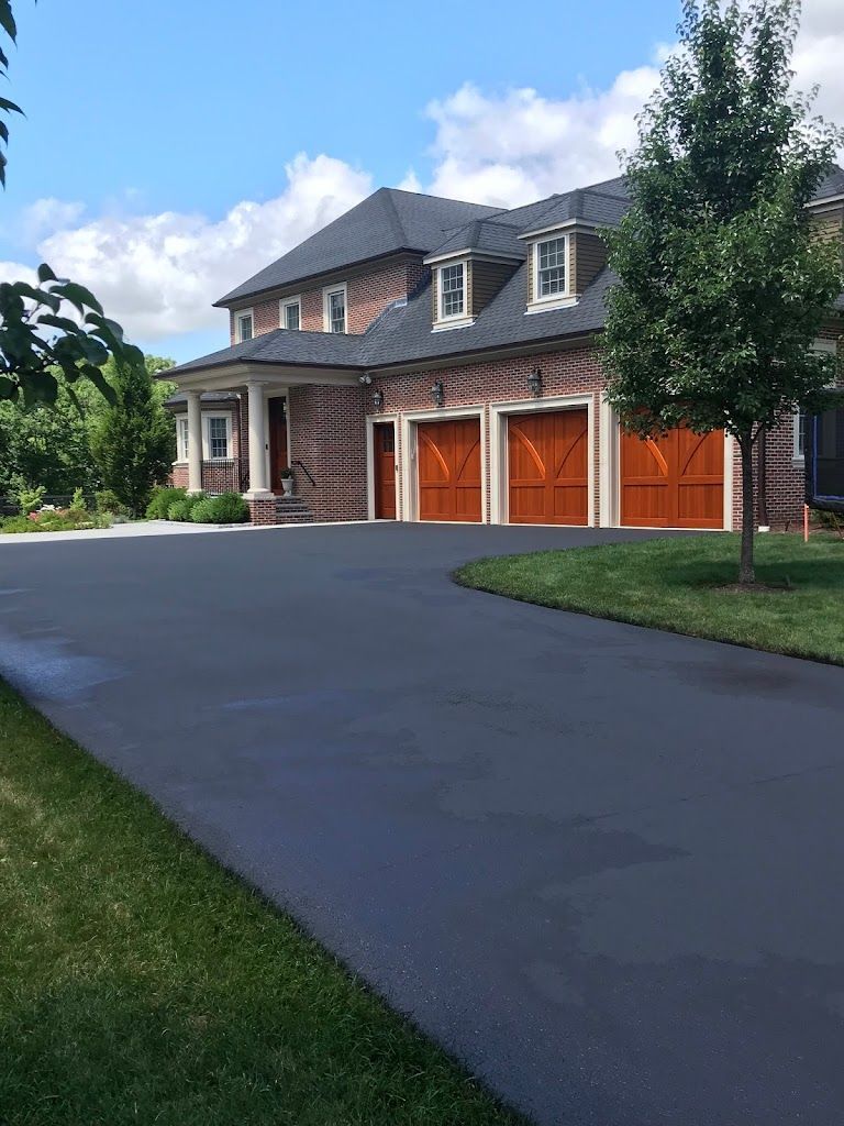 A large brick house with three garage doors and a driveway leading to it.