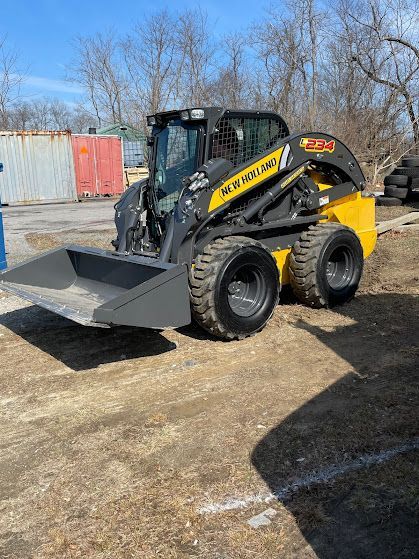 A yellow and black skid steer loader with a large bucket is parked in a parking lot.