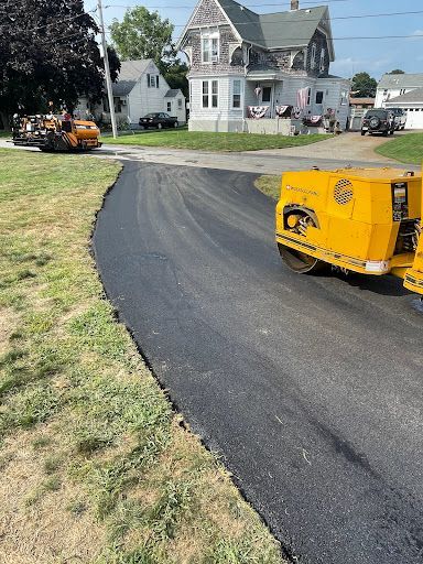 A yellow truck is driving down a road next to a house.