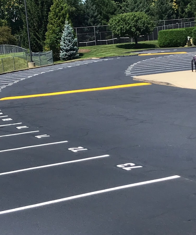 A driveway with a mailbox on the side of it surrounded by trees and grass.