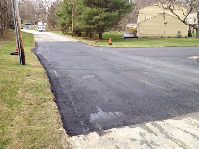 A newly paved road with a house in the background.