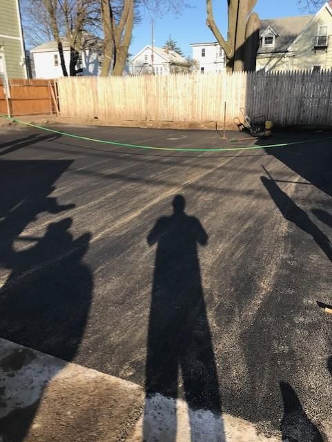 A shadow of a person is cast on the ground in a parking lot.