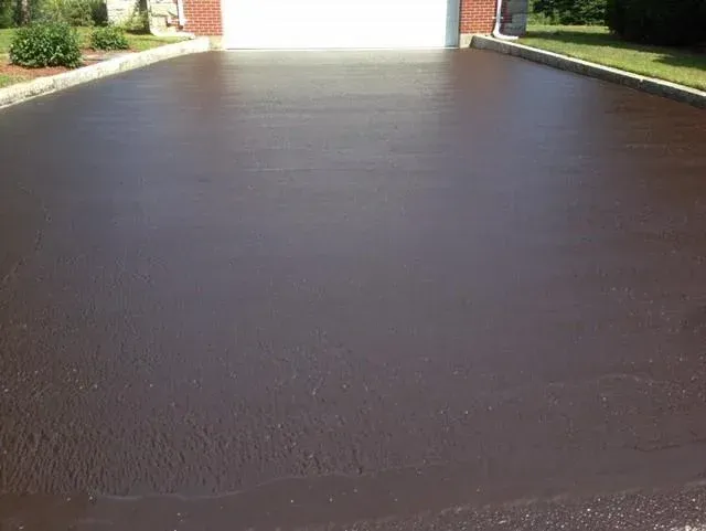 A brown driveway with a garage in the background.