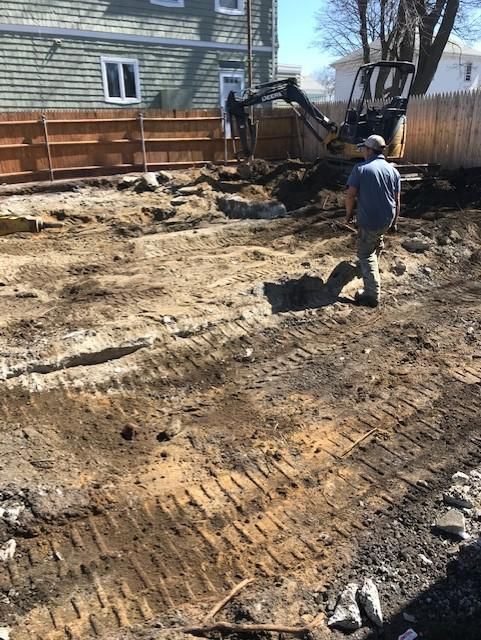 A man is standing in a dirt field next to an excavator.