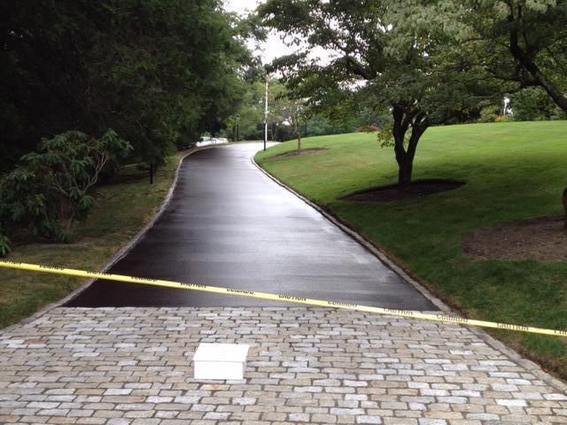 A brick driveway with a yellow tape along the side of it