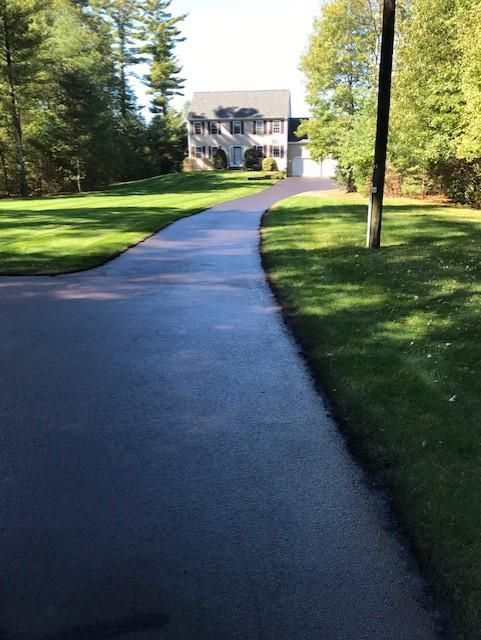 A driveway leading to a house with a lot of grass