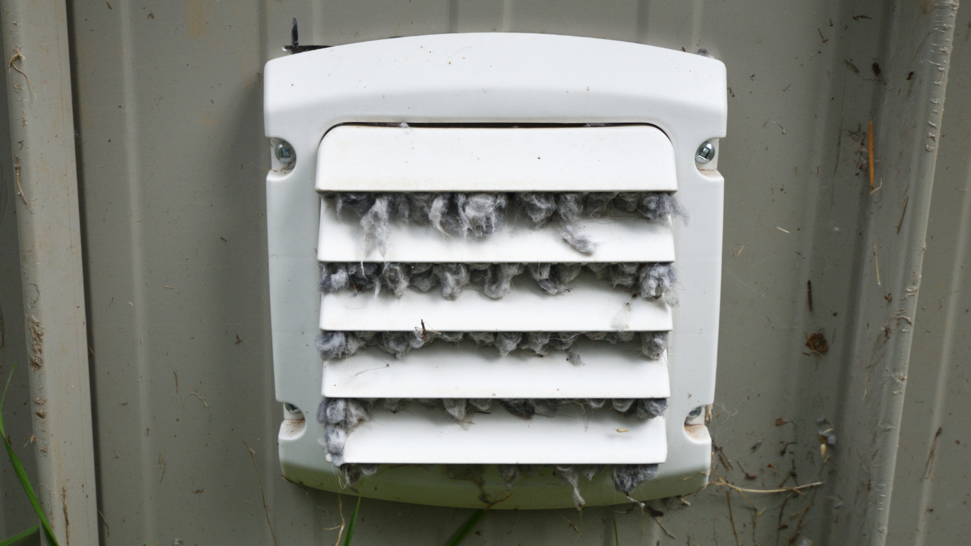 A white vent on a wall with birds sitting on it.