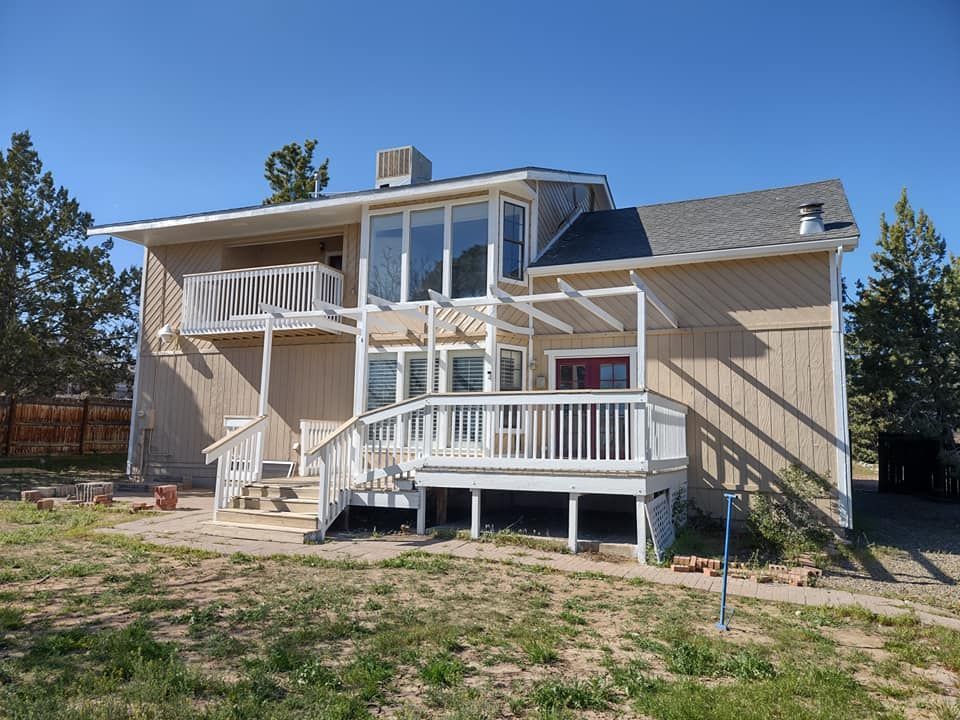 The back of a house with a large deck and stairs re painted