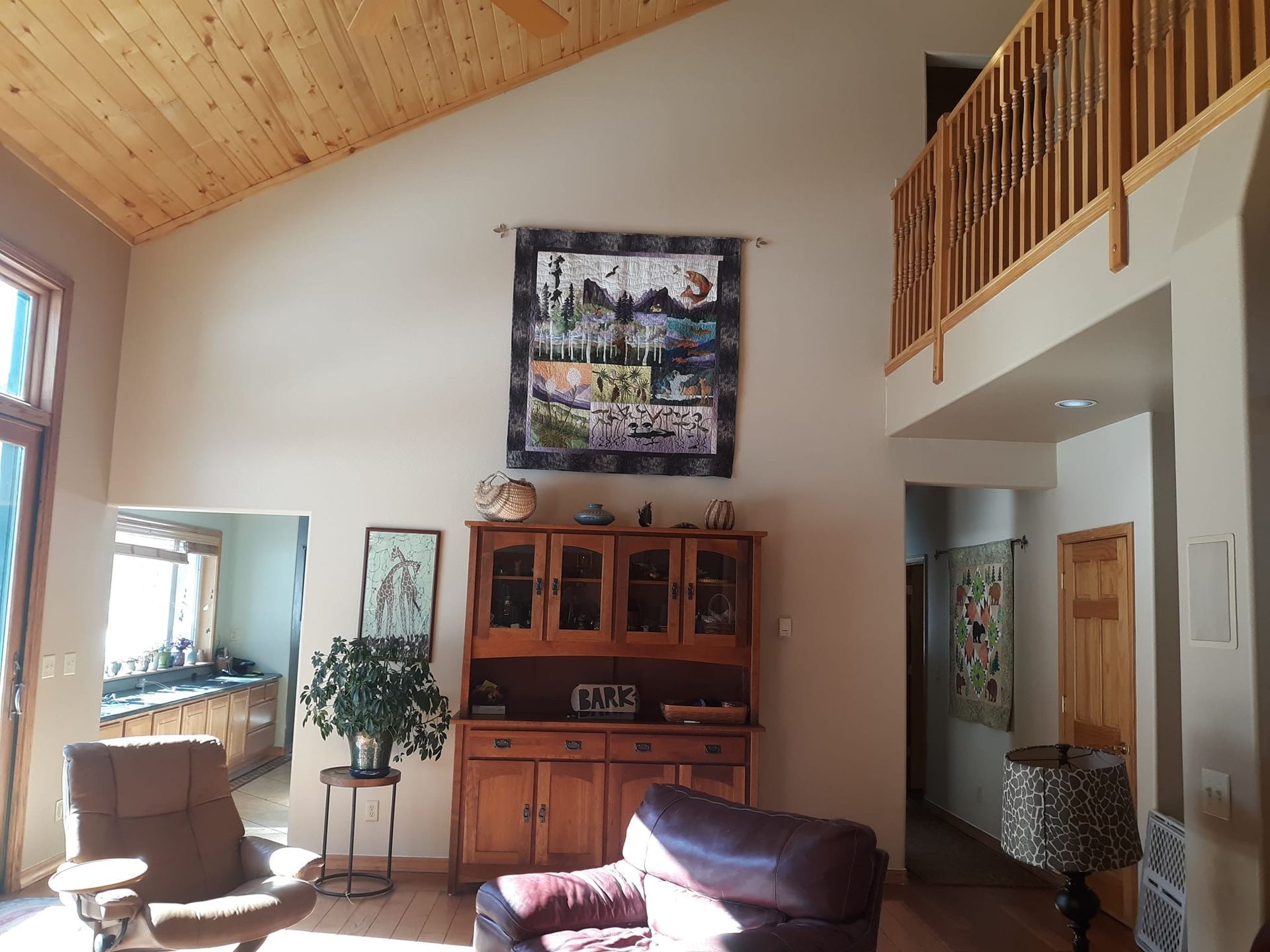 A living room with a vaulted ceiling and a quilt on the wall
