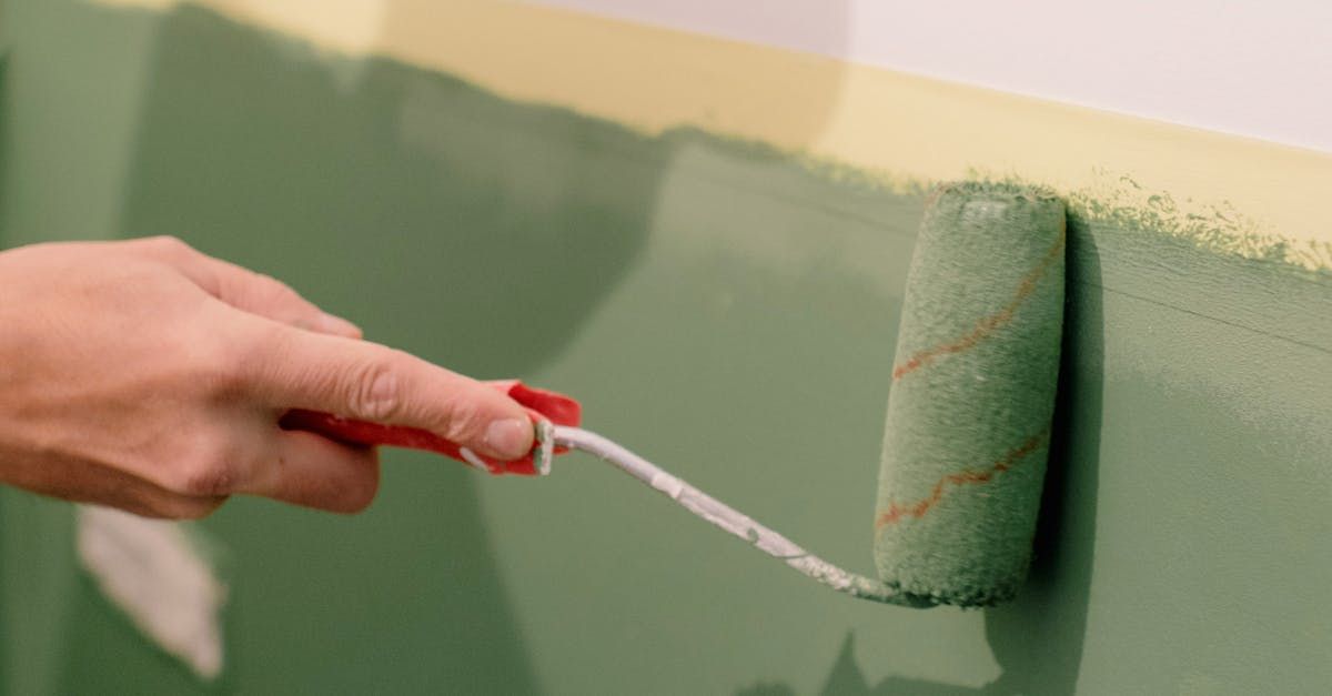 A person is painting a wall with a paint roller.