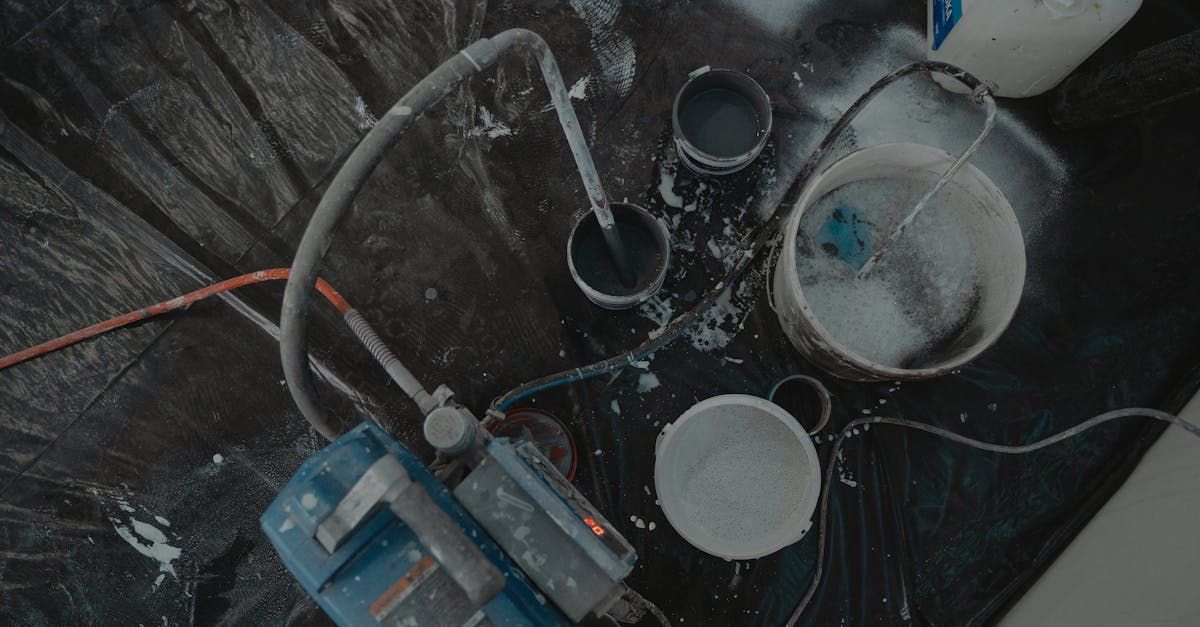 A water pump is sitting on the floor next to buckets of water.