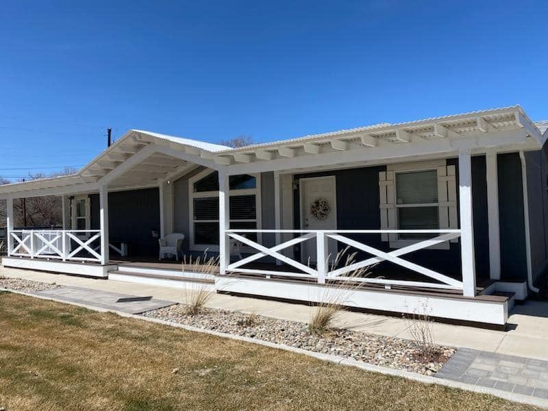 A painted black house with a white porch and a blue sky in the background.