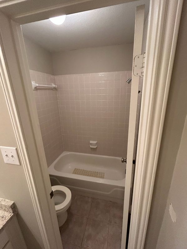 A bathroom with a tub , toilet and shower.