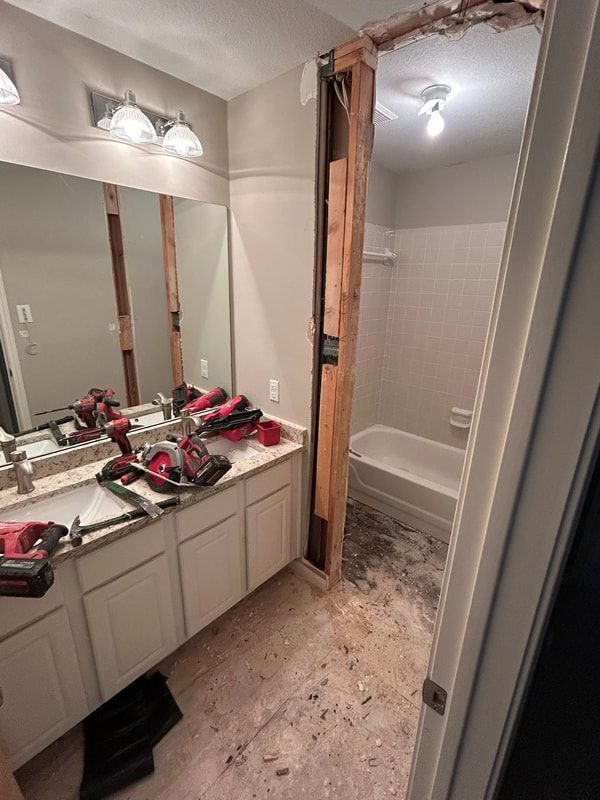 A bathroom with a sink , mirror and bathtub being remodeled.