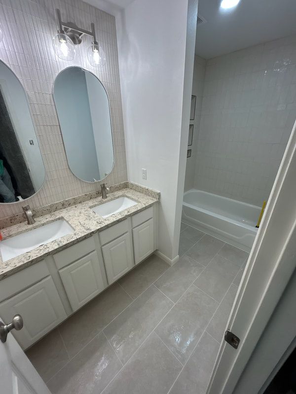 A bathroom with two sinks , two mirrors and a bathtub.