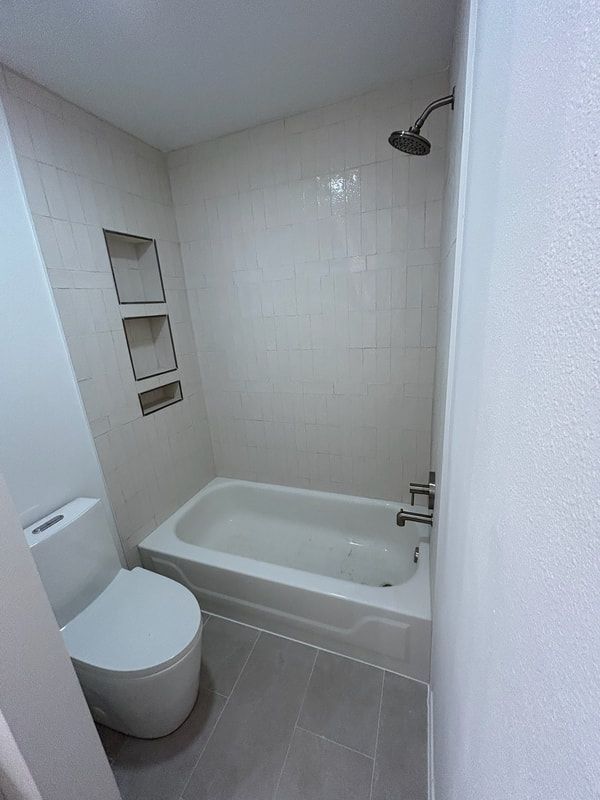 A bathroom with a toilet , bathtub and shower.