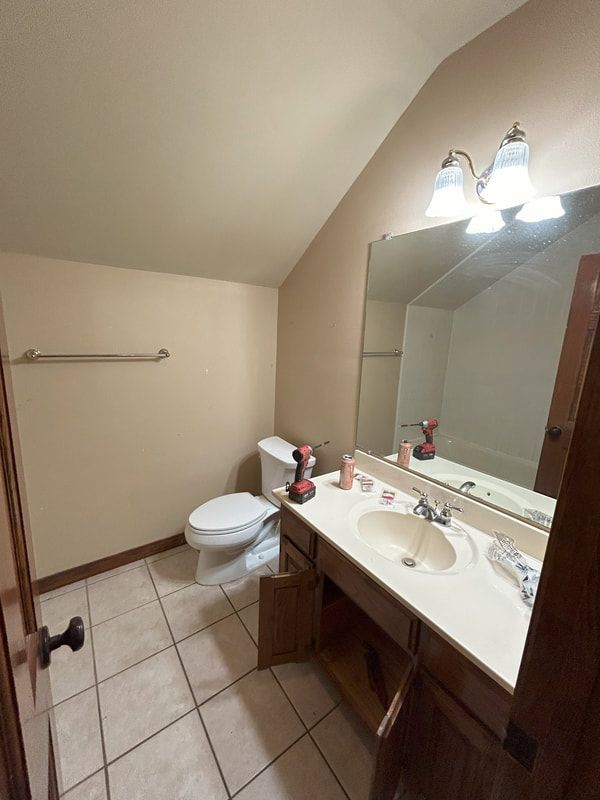 A bathroom with a toilet , sink and mirror.