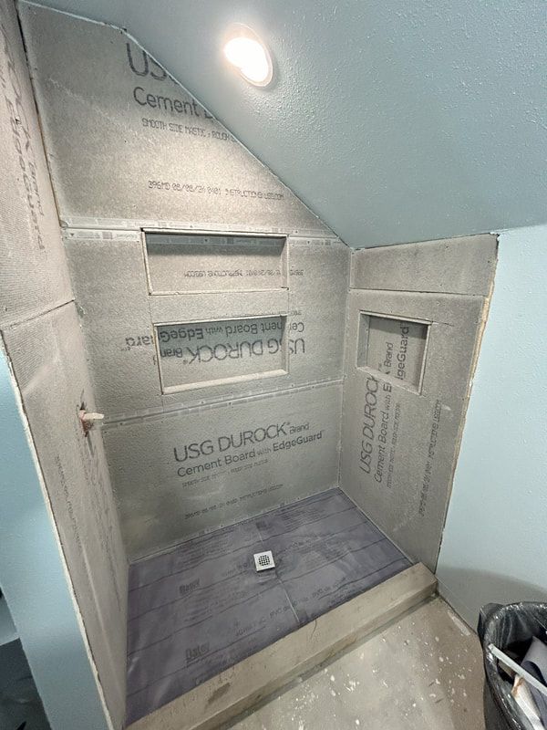 A shower is being built in a bathroom under a staircase.