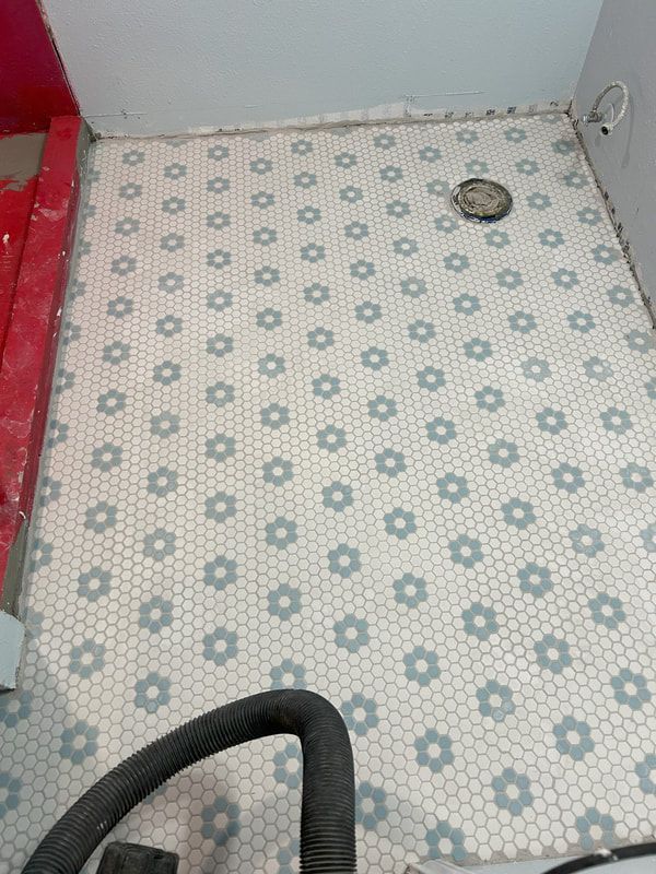 A vacuum cleaner is sitting on a tiled floor in a bathroom.