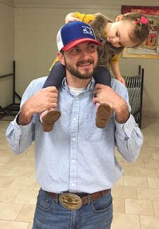 A man is carrying a little girl on his shoulders.