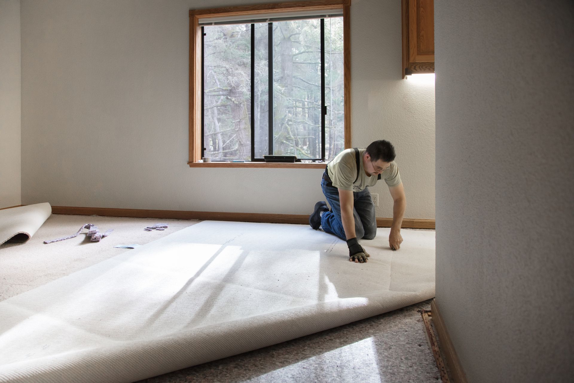 A man is kneeling down on a carpeted floor in a room.
