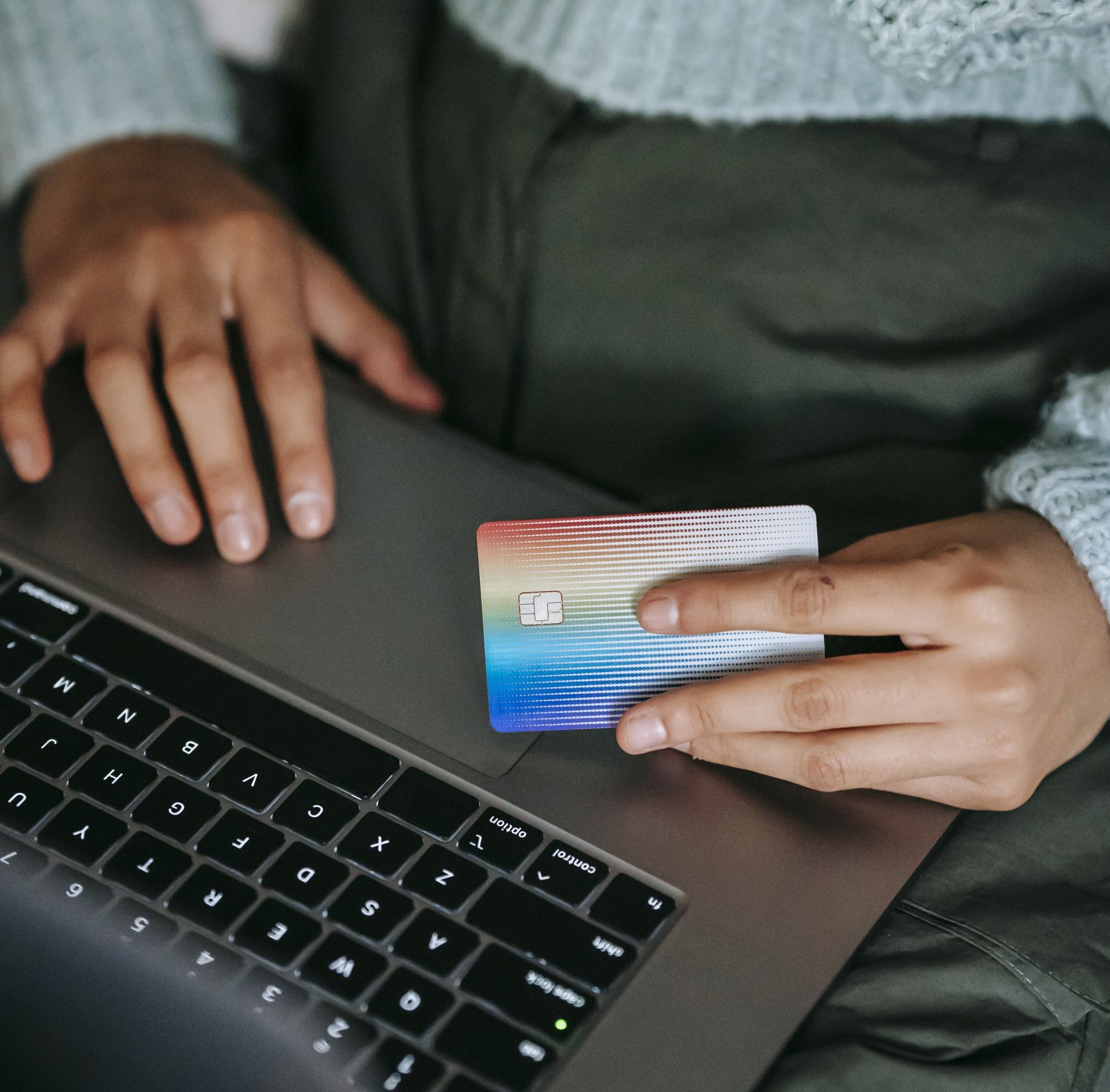 a person is holding a credit card in front of a laptop computer .