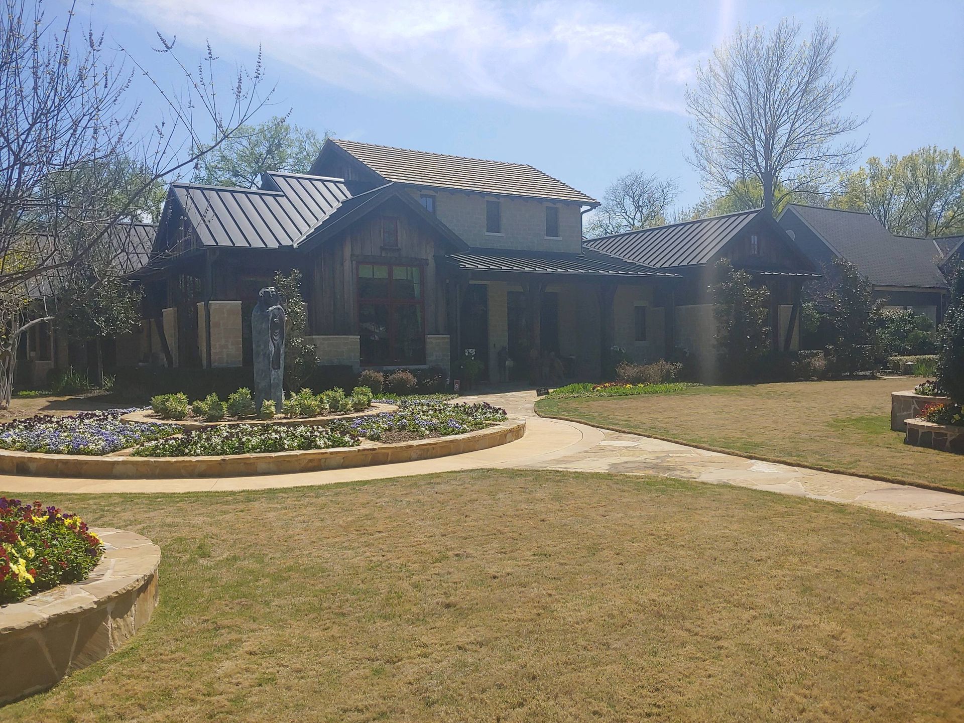 House with dark metal roof, wood siding, and awning over a porch. A brick path leads to the entrance.