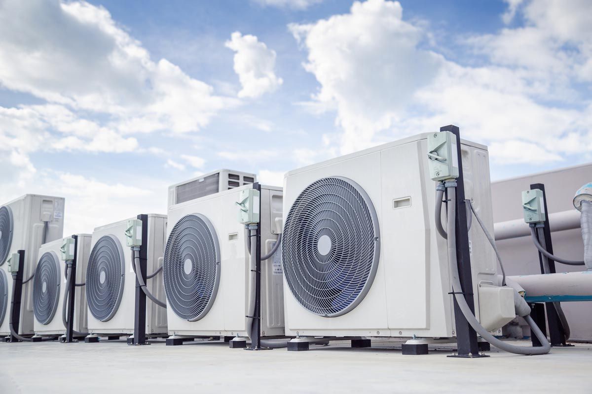 A row of air conditioners are sitting on top of a building.