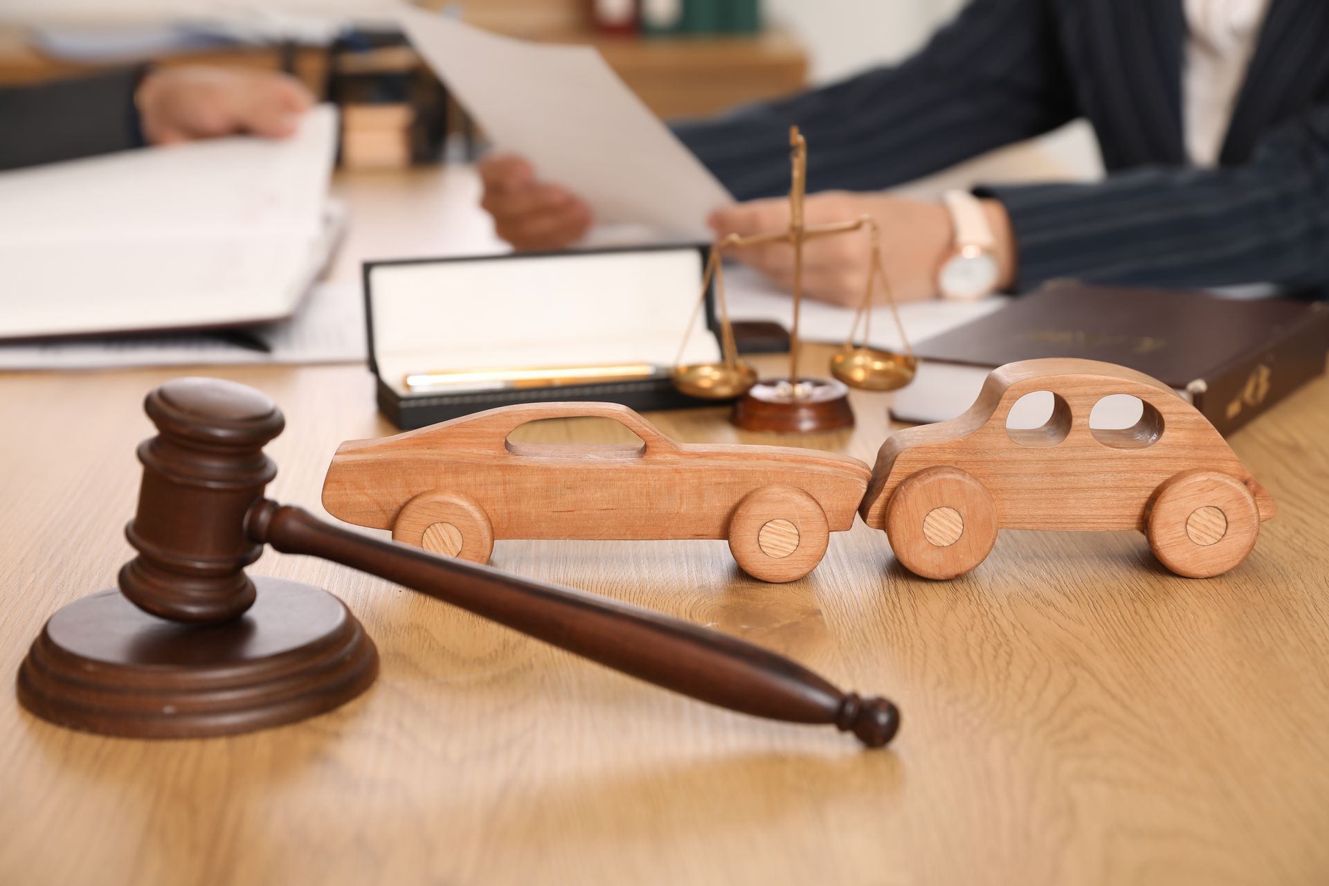 Wooden car models and legal tools on the desk.