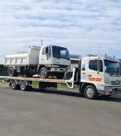 Tow Truck Transporting a Broken Car Along a City Street | Shellharbour, Nsw