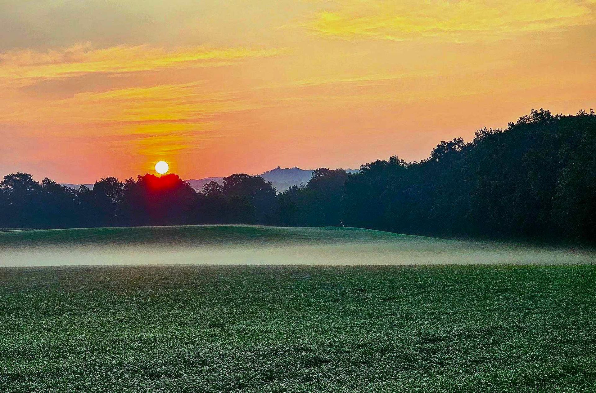 The sun is setting over the ocean and the waves are crashing on the beach.