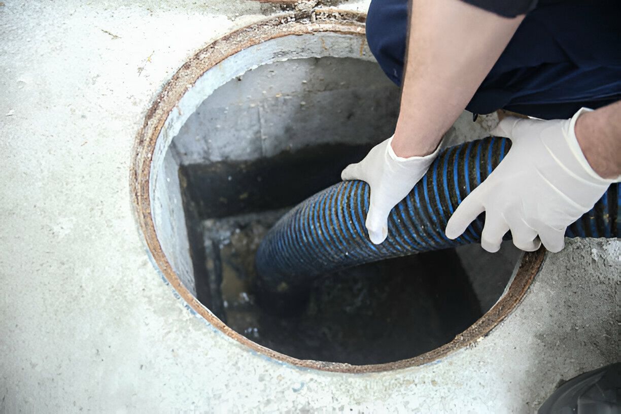 A person is using a vacuum hose to clean a manhole.