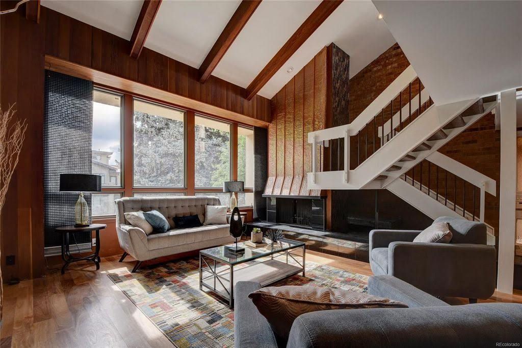 A living room with a couch , chairs , coffee table and stairs.