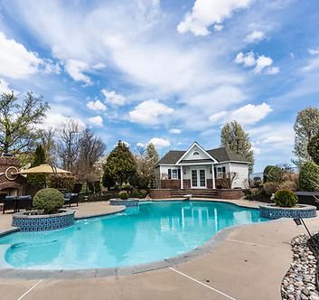 There is a large swimming pool in the backyard of a house.