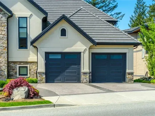A large house with two garage doors and a driveway.
