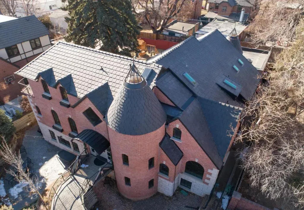 An aerial view of a large brick house with a tower on top of it