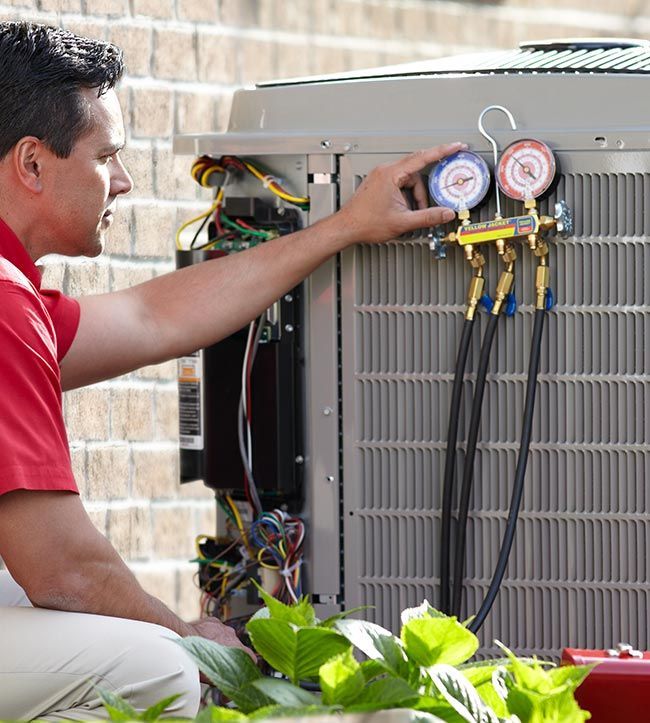 A man in a red shirt is working on an air conditioner