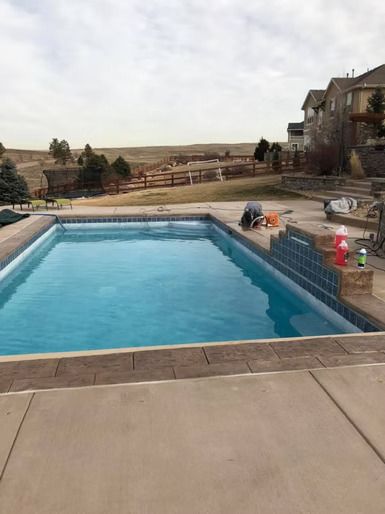 There is a large swimming pool in the backyard of a house.