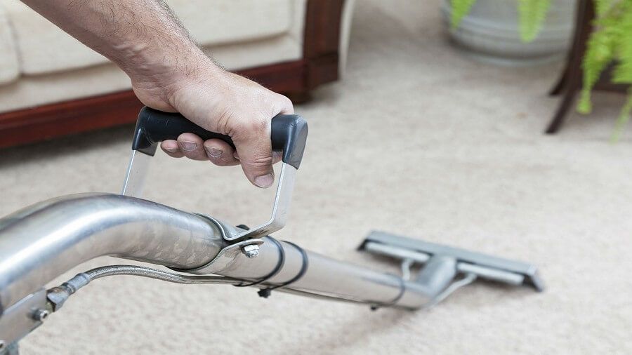 A person is using a vacuum cleaner to clean a carpet in a living room.